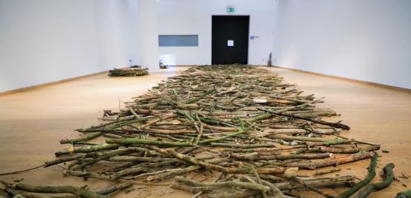 Instalacja artystyczna - gałęzie leżą na podłodze.