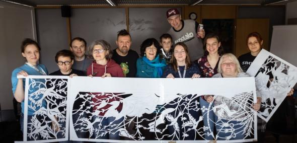 Grupa pracowników Muzeum POLIN trzyma przed sobą szablony stworzone podczas warsztatów muralowych.