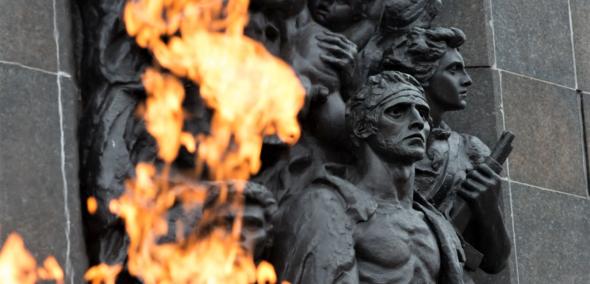 Fragment pomnika Bohaterów Getta w Warszawie, widziany zza płomienia pochodni