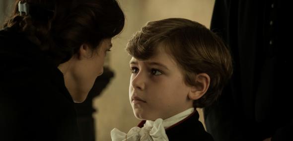 Kadr z filmu "Porwany" - kobieta łapie za łańcuszek wiszący na szyi małego odświętnie ubranego chłopca.