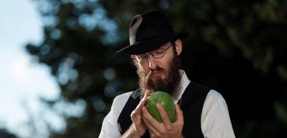 Kadr z filmu "Początek". Ortodoksyjny Żyd trzyma w dłoniach zielone jabłko.