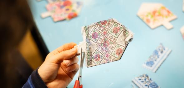 Дитина вирізає з паперу різнокольорові ханукальні дзиги з квітковими мотивами.