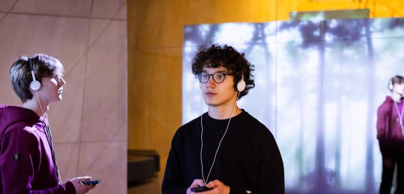 Dwóch nastolatków zwiedza wystawę stałą Muzeum POLIN, korzystając z audiogry.
