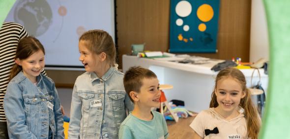 Czworo uśmiechniętych dzieci stoi w Miejscu edukacji rodzinnej w Muzeum POLIN.