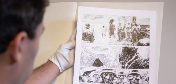 Przemysław Kaniecki ogląda leżącą na stole planszę komiksu "Achtung Zelig!".