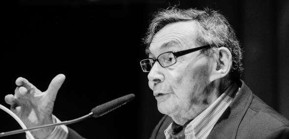 Marian Turski przemawia przy mównicy.