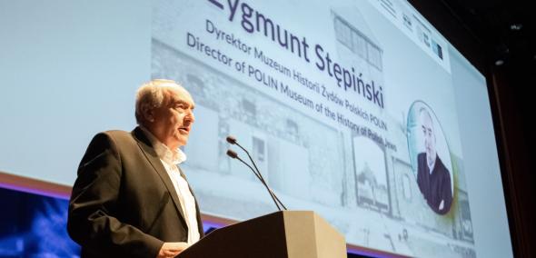 Zygmunt Stępiński stoi przy mównicy w Audytorium podczas konferencji Muzeum POLIN i Ministerstwa Sprawiedliwości.