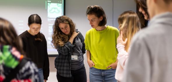Dwie kobiety i grupa nastolatków stoją przed stołem, na którym leżą prace plastyczne z motywami żydowskimi, np. gwiazdą Dawida.