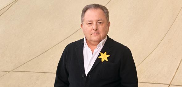 Robert Makłowicz ma przypięty żonkil do czarnego swetra.
