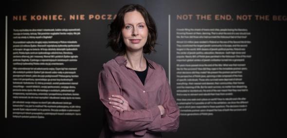 Zuzanna Schnepf-Kołacz na tle planszy z napisem "1945. Nie koniec, nie początek".