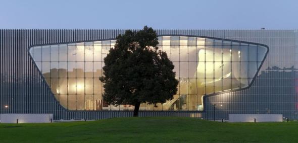 Budynek Muzeum POLIN od strony ulicy Anielewicza - szyba rozświetlona jasnym światłem.