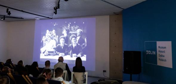 Grupa osób ogląda film w galerii "Dziedzictwo" Muzeum POLIN.