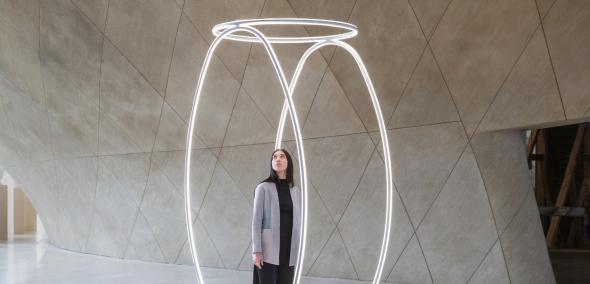 Dziewczyna stoi w środku instalacji świetlnej "Echo" prezentowanej w holu głównym Muzeum POLIN.