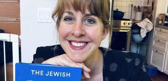 Na zdjęciu Leah Koenig, trzyma przed sobą najnowszą swoją książkę pt. "The Jewish Cookbook"
