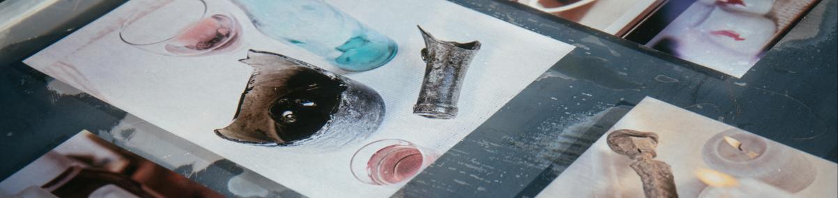 Gablota szklana, w której pokazane są zdjęcia przedmiotów z badań archeologicznych: butelki, przedmioty metalowe, pokazane na wystawie "Tu Muranów" w Muzeum POLIN