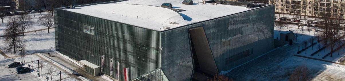 Budynek Muzeum POLIN w Warszawie, widziany z góry, w otoczeniu innych budynków osiedla Muranów. Zdjęcia zrobione zimą, dach muzeum oraz okoliczne chodniki i ulice pokryty jest śniegiem.