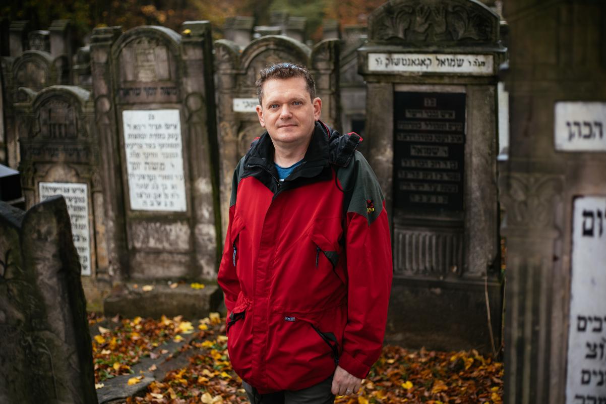Paweł Kulig stoi wśród macew na Nowym Cmentarzu Żydowskim w Łodzi