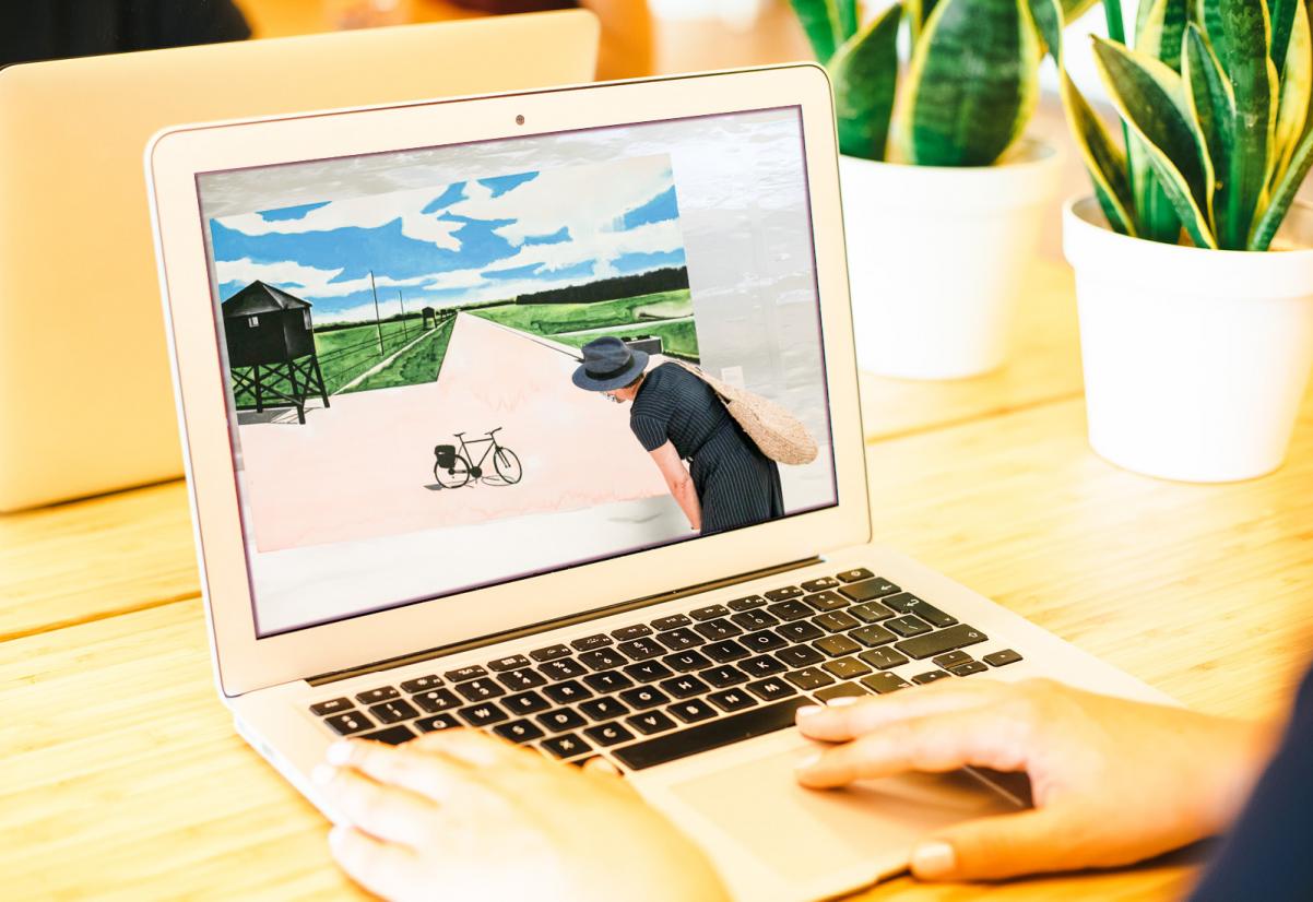 Otwarty laptop. Na jego ekranie wyświetla się praca Wilhelma Sasnala - mężczyzna przygląda się rowerowi stojącemu na terenie obozu koncentracyjnego.