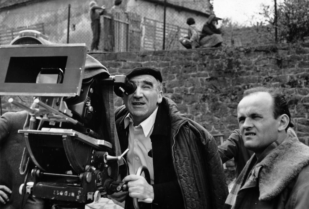 Czarno-biała fotografia. Aeksander Ford patrzy w wizjer dużej kamery, obok stoi drugi mężczyzna