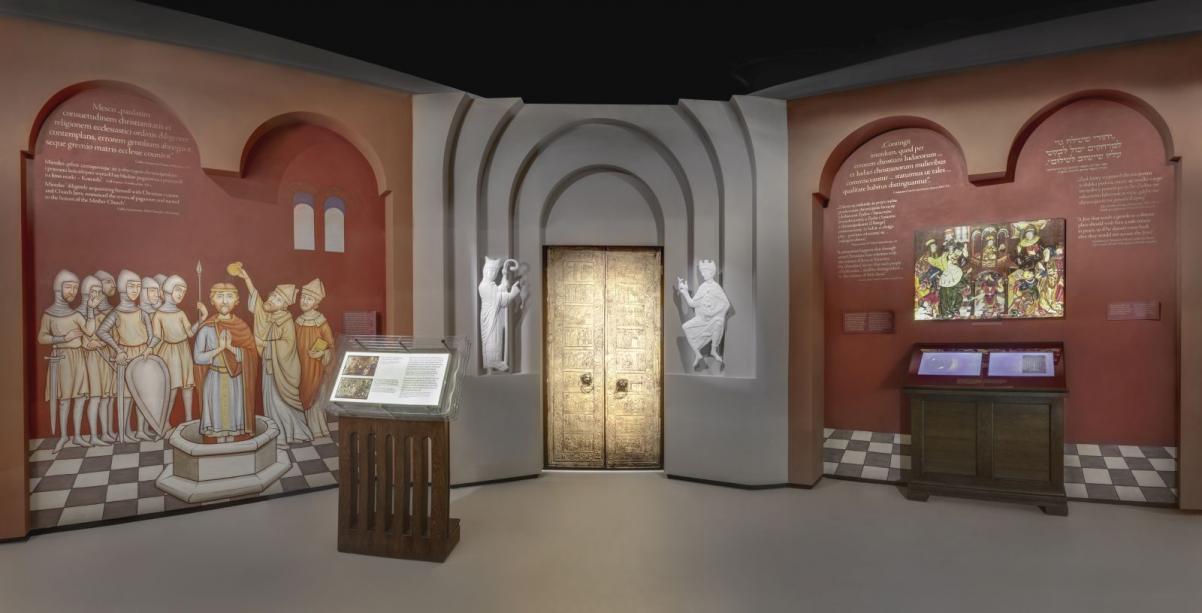 Galeria "Pierwsze spotkania" na wystawie stałej Muzeum POLIN - na bordowych ścianach namalowane postaci króla i rycerzy i złote wrota