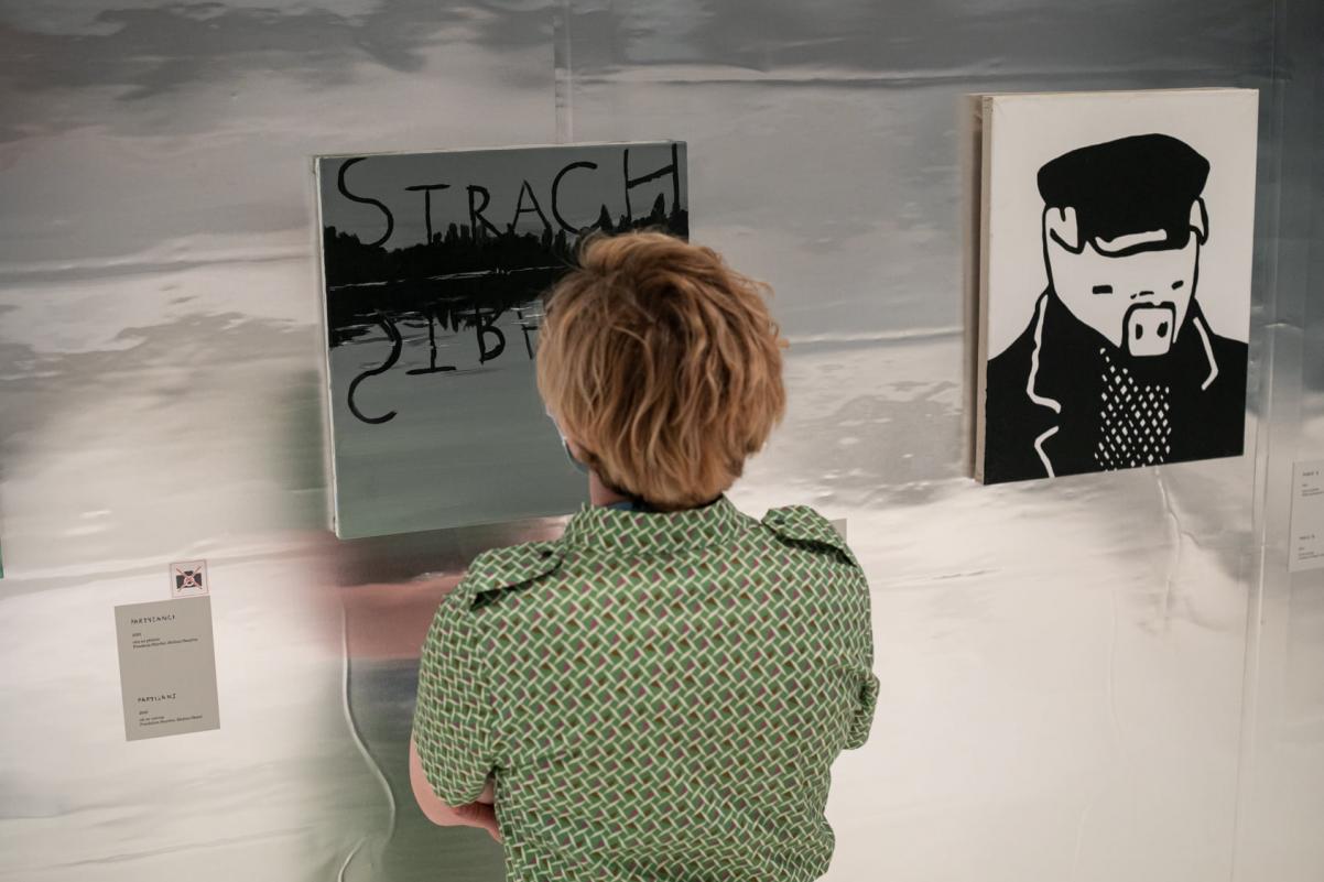 Kobieta przygląda się blisko jednej z pracy na wystawie Wilhelm Sasnal: Taki pejzaż.