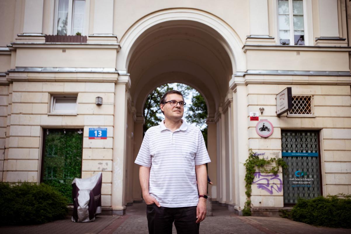 Mariusz Jastrząb stoi przy kamienicy na warszawskim Muranowie.
