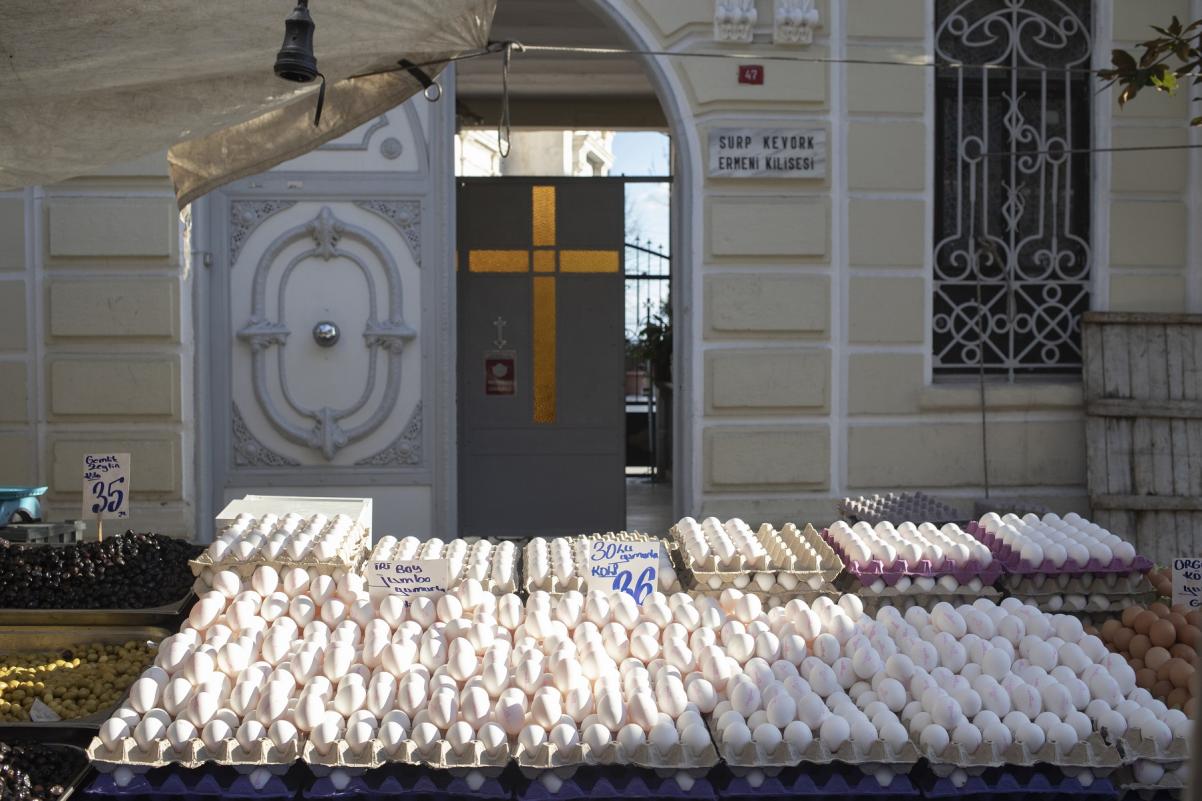 Jajka wyłożone w pudełkach na bazarze. Za stoiskiem na drzwiach znajduje się katolicki krzyż.
