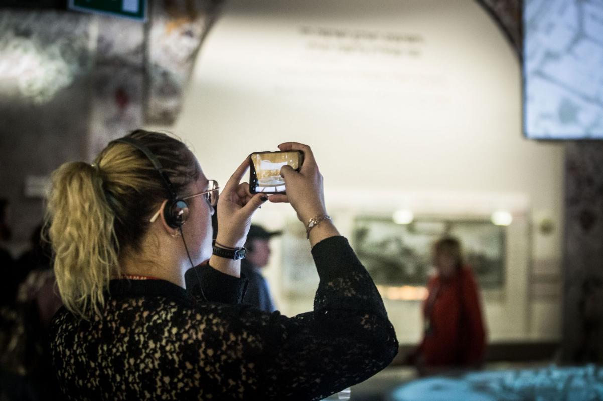 Kobieta robi zdjęcie smartfonem na wystawie stałej w Muzeum POLIN.