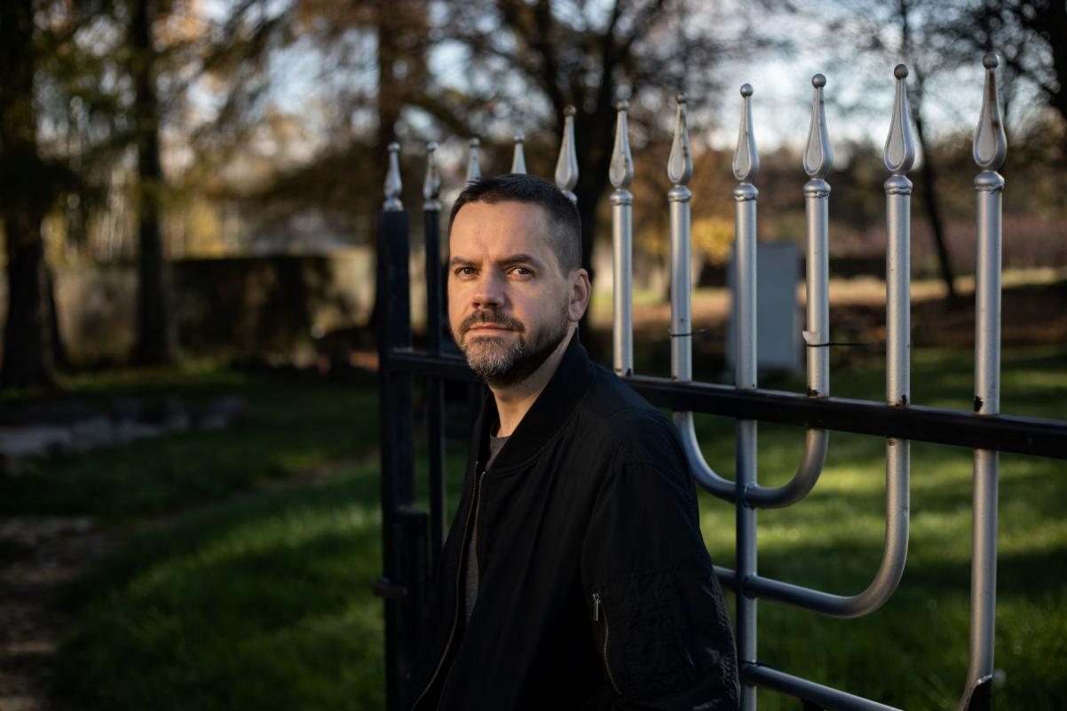 Michał Szaflarski stoi przy bramie cmentarza żydowskiego.