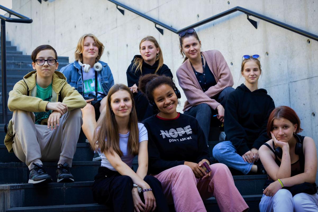 Grupa młodzieży siedzi na schodach przy wejściu do pracowni kulinarnej "u Fani" w Muzeum POLIN.