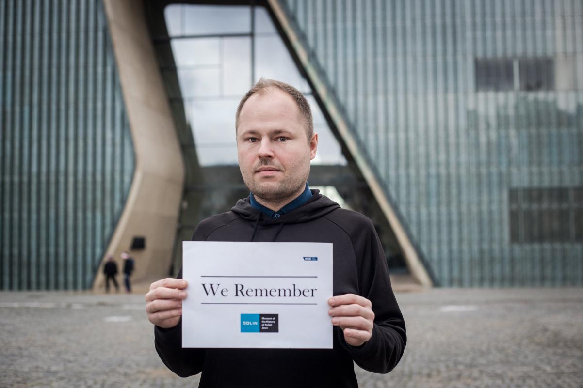Radosław Wójcik, a worker of POLIN Museum, holds a paper with We Remember hashtag.