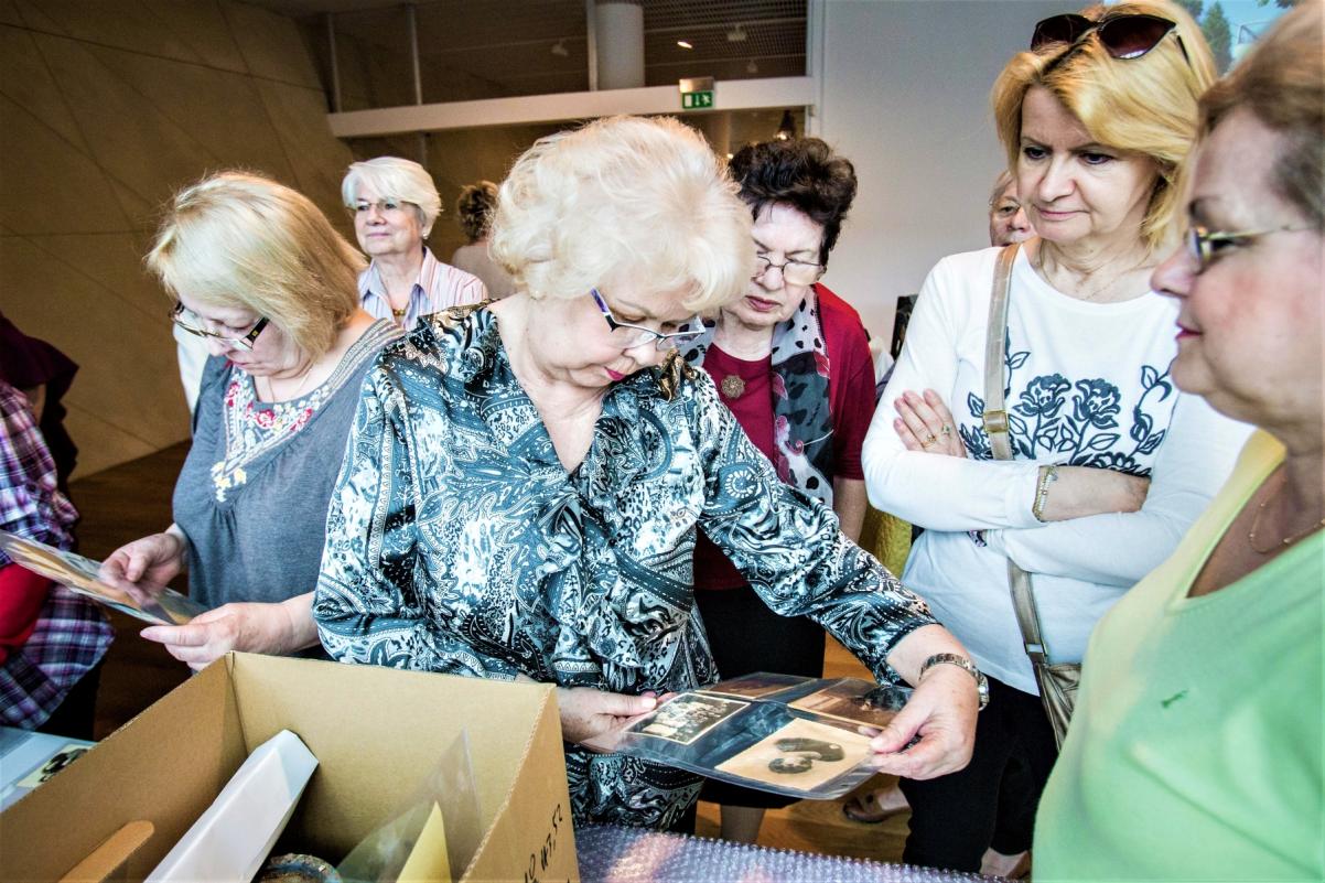 Seniorki oglądają zdjęcia podczas spotkania.