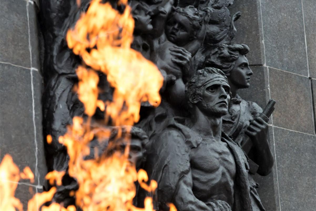 Fragment pomnika Bohaterów Getta w Warszawie, widziany zza płomienia pochodni