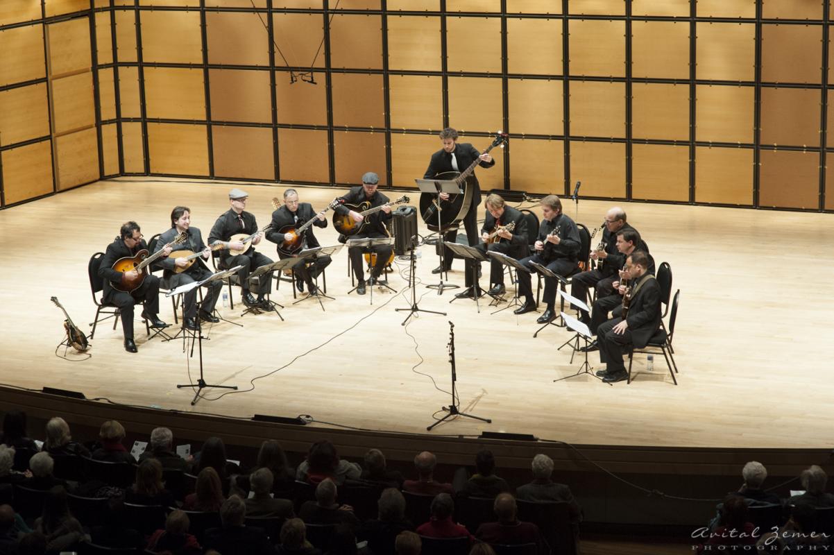 Widok z lotu ptaka na scenę, na której 10 muzyków z Ger Mandolin Orchestra sieci w półokręgu i gra utwór
