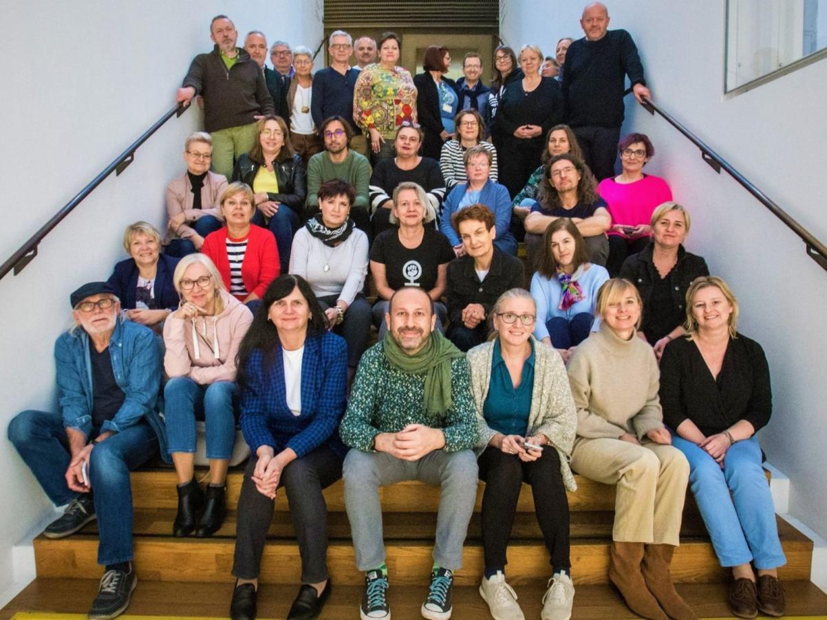 Grupa nauczycielek i nauczycieli siedzi na schodach w Muzeum POLIN.