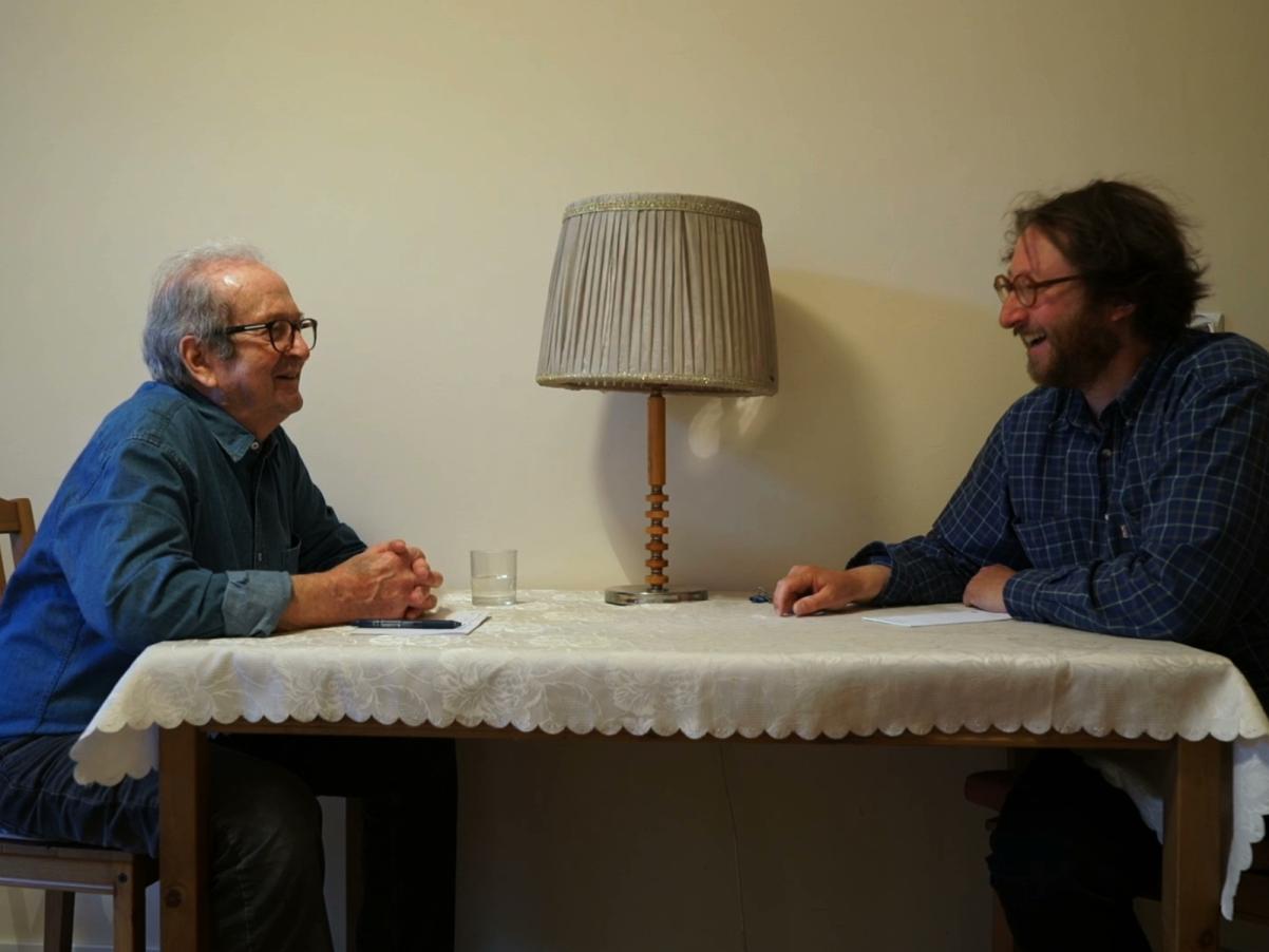 Kadr z filmu "Zamek mojego ojca". Ojciec i syn siedzą przy stole nakrytym obrusem.