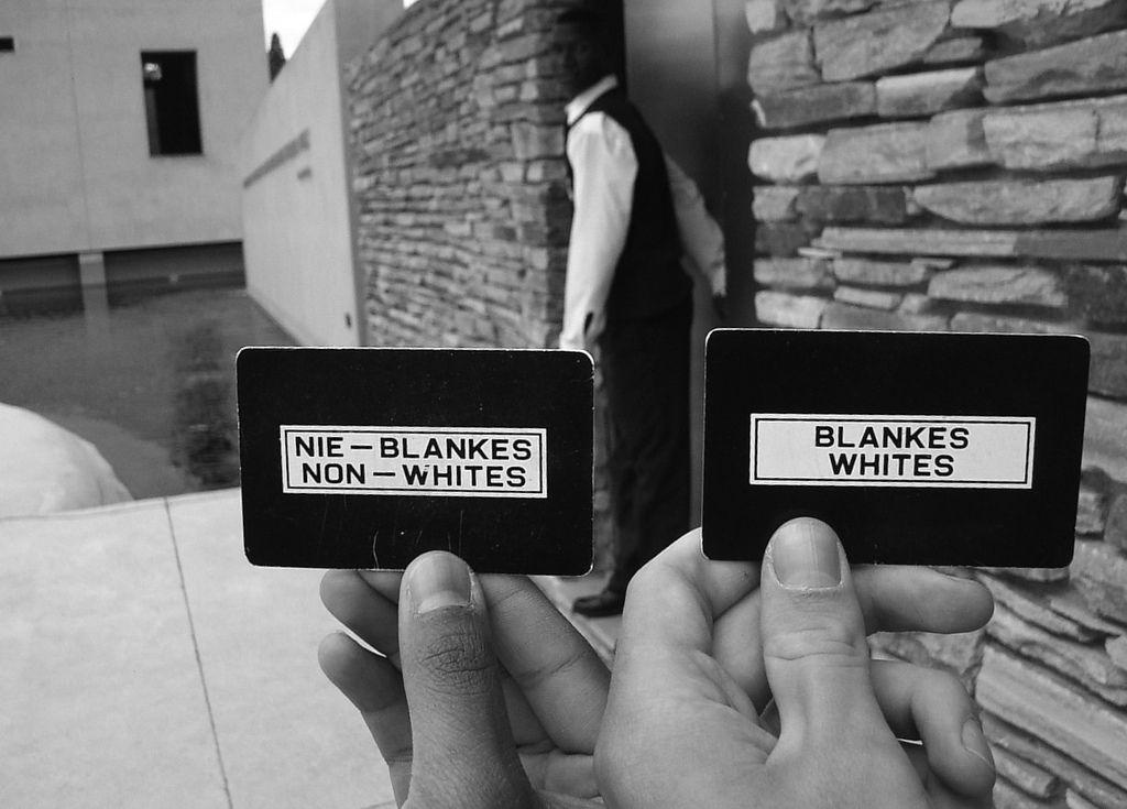 Dwie osoby trzymają tabliczki z napisami: "nie-blankes, non-whites", "blankes-whites".