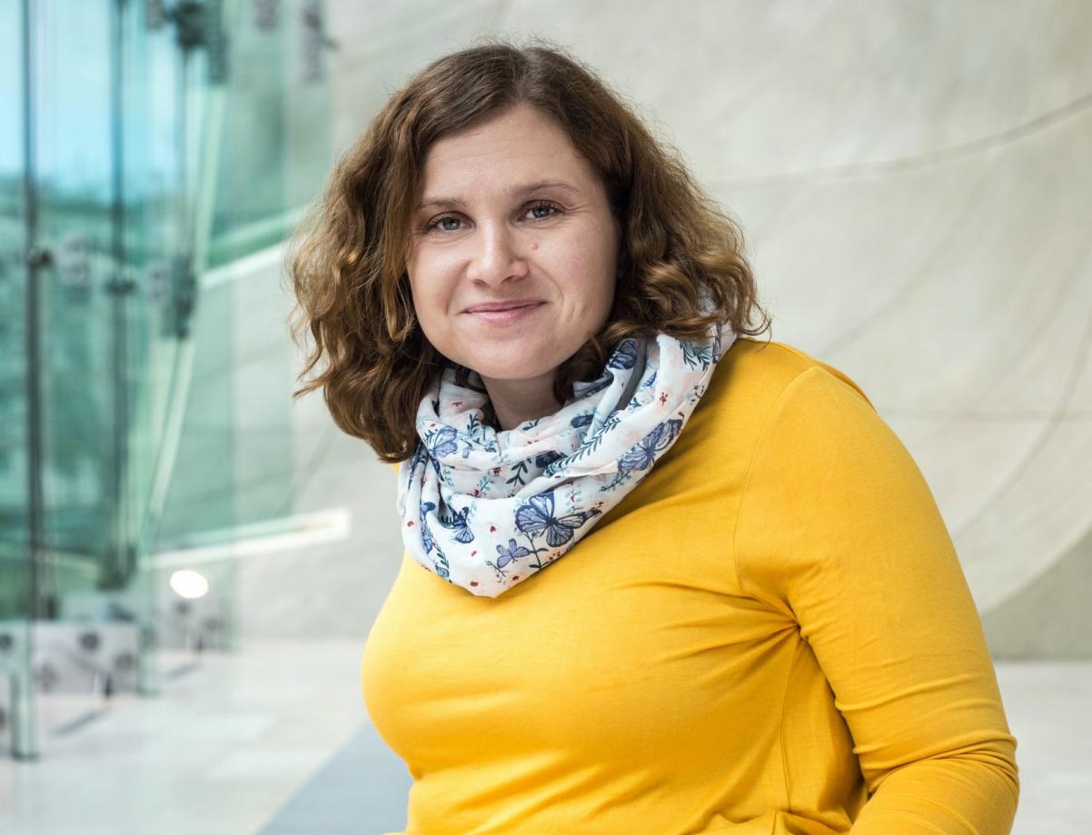 Wioleta Jóźwiak - koordynatorka ds. dostępności Muzeum POLIN. Kobieta w żółtej tunice i apaszce w motyle.