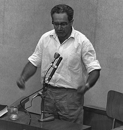 Israel Guttman. Czarno-białe zdjęcie przedstawia stojącego mężczyznę w białej koszuli.