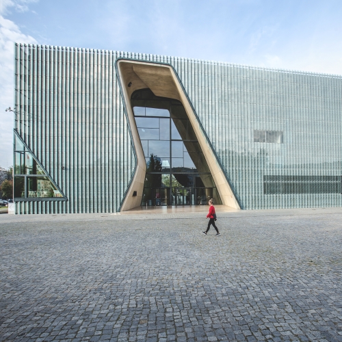 POLIN Museum building on Bohaterów Getta Square. A man walks by it.