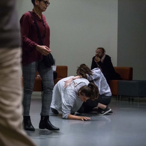Two women in white shirts are kneeling next to each other on the floor.