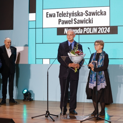 Ewa Teleżyńska-Sawicka i Paweł Sawicki stoją na scenie podczas finału konkursu Nagroda POLIN 2024. Obok, w rogu stoją Zygmunt Stępiński i Piotr Wiślicki.