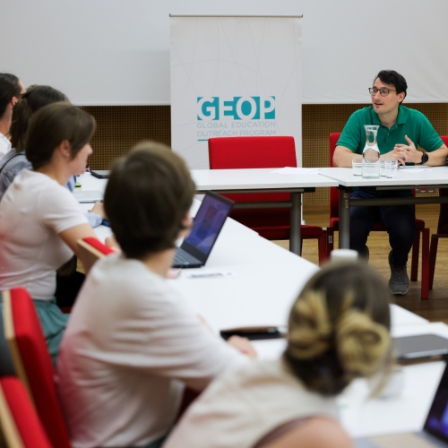 Participants of a scientific conference are sitting in a conference room and talking.