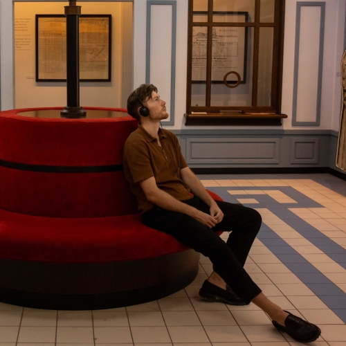 A woman and a man are sitting on a couch in the Core Exhibition in a gallery that resembles a train station.