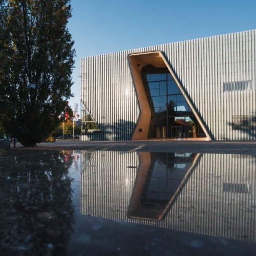 POLIN Museum building is reflected in the surface of the Ghetto Heroes Monument.
