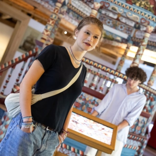 Dwoje nastolatków stoi na wystawie stałej przy rekonstrukcji synagogi z Gwoźdźca.