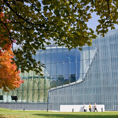 The POLIN Museum building surrounded by autumn trees with colourful leaves.