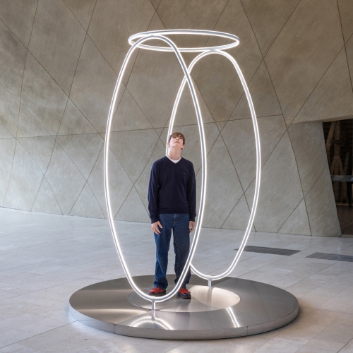 Chłopak stoi wewnątrz instalacji świetlnej "Echo", stojącej w holu głównym Muzeum POLIN.