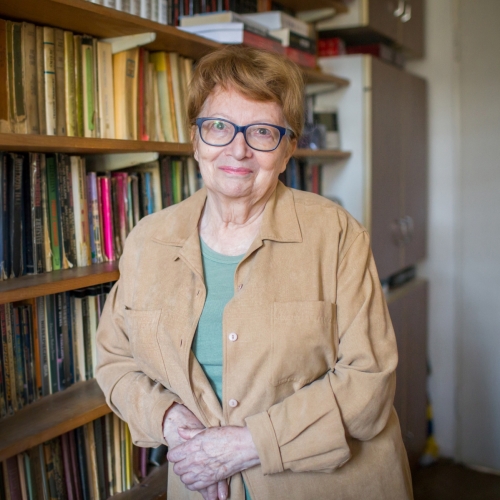 Joanna Sobolewska stoi przy regale z książkami.