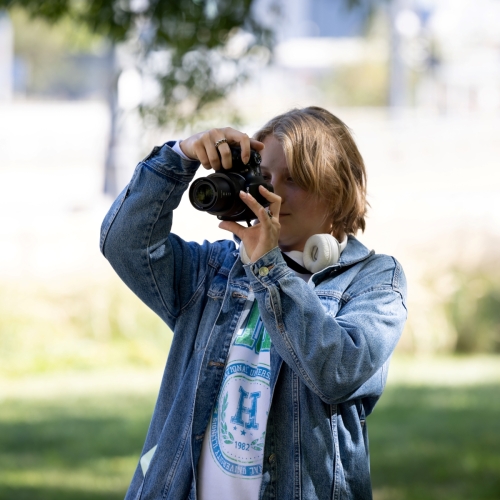 Хлопець робить у парку фотографію фотоапаратом.